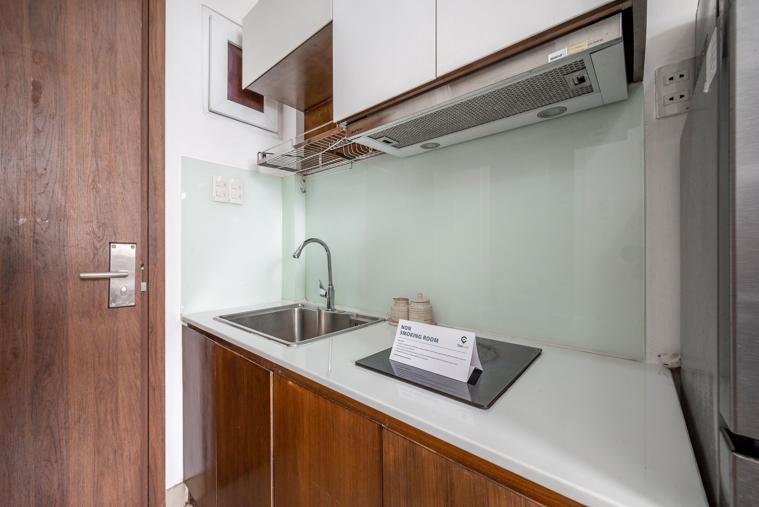 A kitchen with a stainless steel sink, a built-in range hood, and a sign indicating it is a non-smoking room.