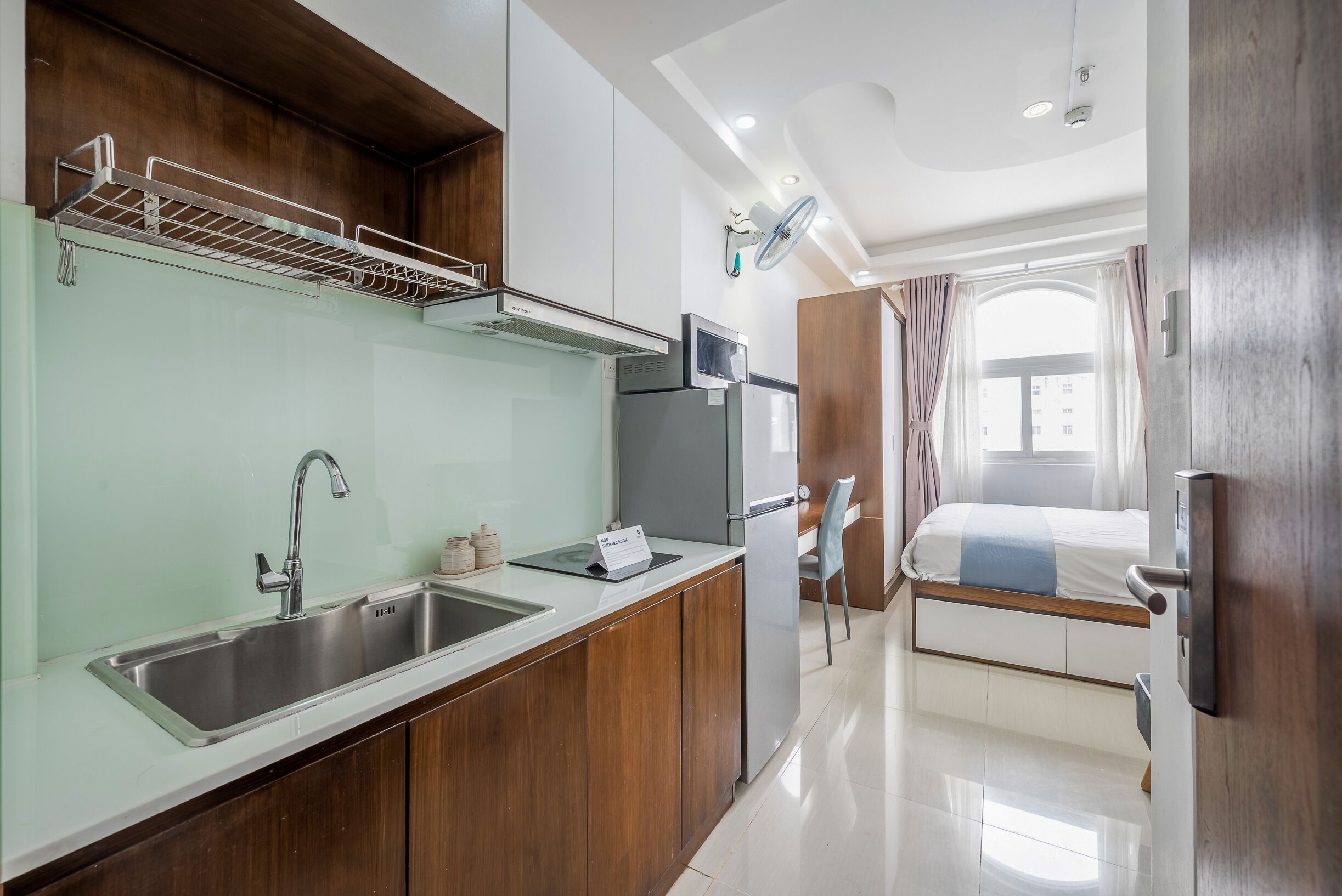 A compact kitchen with a stainless steel sink, a microwave, and a built-in oven.
