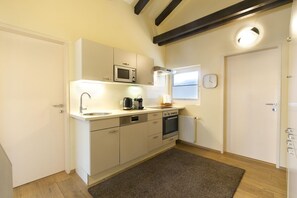 A compact kitchen with white cabinets, a microwave, a coffee maker, and a clock on the wall. - Apartment in Seefeld near Rosshütte Ski Resort (Seefeld in Tirol)