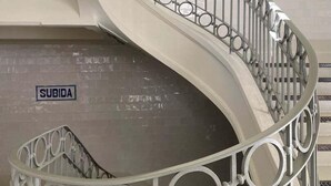 Un escalier en colimaçon avec une rampe métallique et une pancarte indiquant « SUBIDA ».