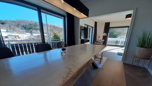 A modern dining area with a long table, chairs, and a view of the outdoors. - Villa in Winterberg near the ski area (Winterberg)