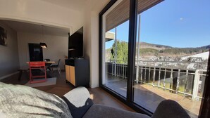 A modern living room with a large sliding glass door leading to a balcony. - Villa in Winterberg near the ski area (Winterberg)