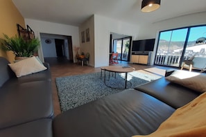 Uma sala de estar moderna com um sofá, uma mesa redonda pequena e vista para o exterior.
