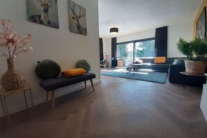 Un salon moderne avec un canapé foncé, un banc et une grande fenêtre.