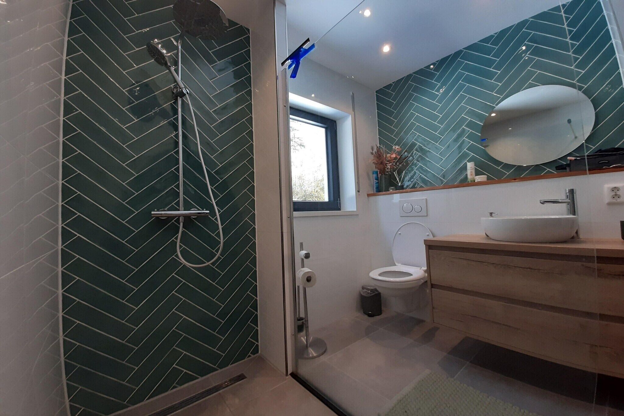 Ein modernes Badezimmer mit einer Duschkabine, einer weißen Toilette und einem Holzlagerflächen mit einem großen Spiegel.