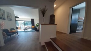 A modern living room with a sofa, a coffee table, and a dining area. There is a staircase leading to a bedroom with a bunk bed. - Villa in Winterberg near the ski area (Winterberg)