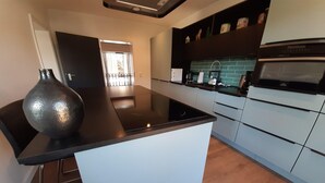 A modern kitchen with a black countertop, white cabinets, and a built-in oven. - Villa in Winterberg near the ski area (Winterberg)