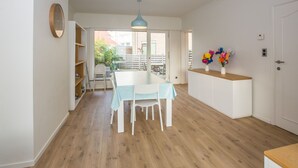 Una cocina moderna con encimera blanca, una lámpara colgante azul y vistas al patio trasero a través de puertas de cristal.