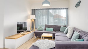 Una sala de estar moderna con un sofá, un televisor, una lámpara y una mesita de madera.