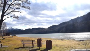 Un parque junto al lago con bancos y un contenedor de basura.