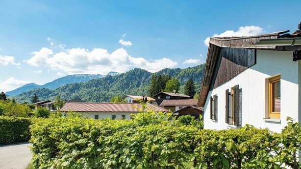 Una zona residencial con casas, cielo despejado y montañas al fondo.