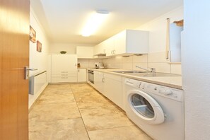 A compact kitchen with a washing machine, a sink, and cabinets.