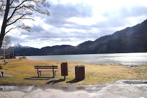 A lakeside park with benches, a trash bin, and a picnic table.
