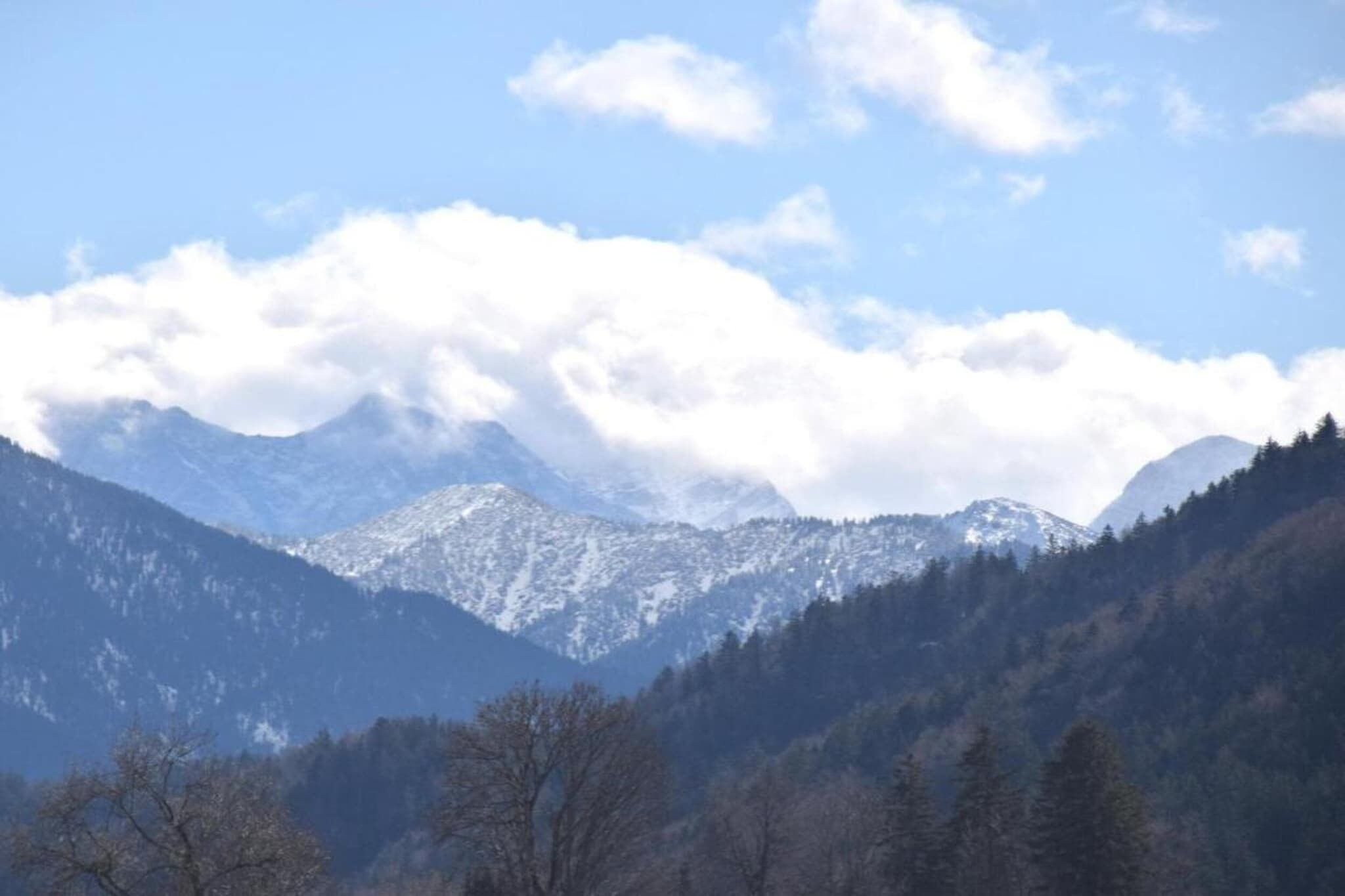 A mountainous landscape with snow-covered peaks and a clear sky.