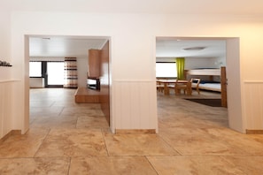A modern hotel room with a tiled floor, a wooden bench, a bed, and a small table with chairs. - Family Escape with Pool (Nesselwang-Reichenbach)