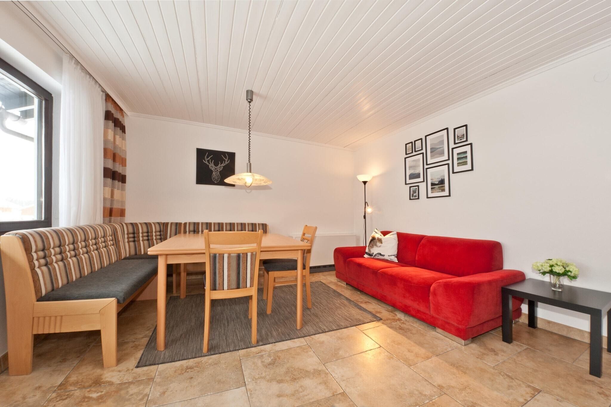 Un salon moderne avec une table à manger en bois, un canapé rouge et un banc.
