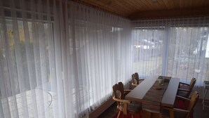 A dining area with a table and chairs, a radiator, and sheer curtains. - Garden Apartment in Füssen (Füssen)