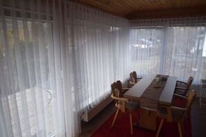 A dining area with a long table, chairs, and a red rug.