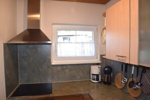 A kitchen with a stainless steel range hood, a window with a view, and wooden cabinets. - Gemütlicher Füssener Rückzugsort in der Nähe des Sees (Füssen)