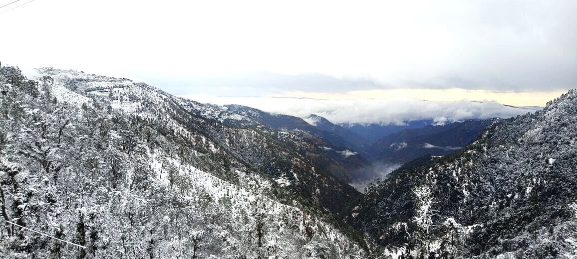 A snow-covered mountain landscape with a valley and a cable car line.