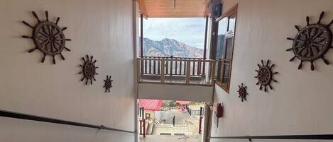 Un escalier menant à un balcon d’où l’on peut admirer la vue sur les montagnes, décoré de motifs représentant des roues de navire.