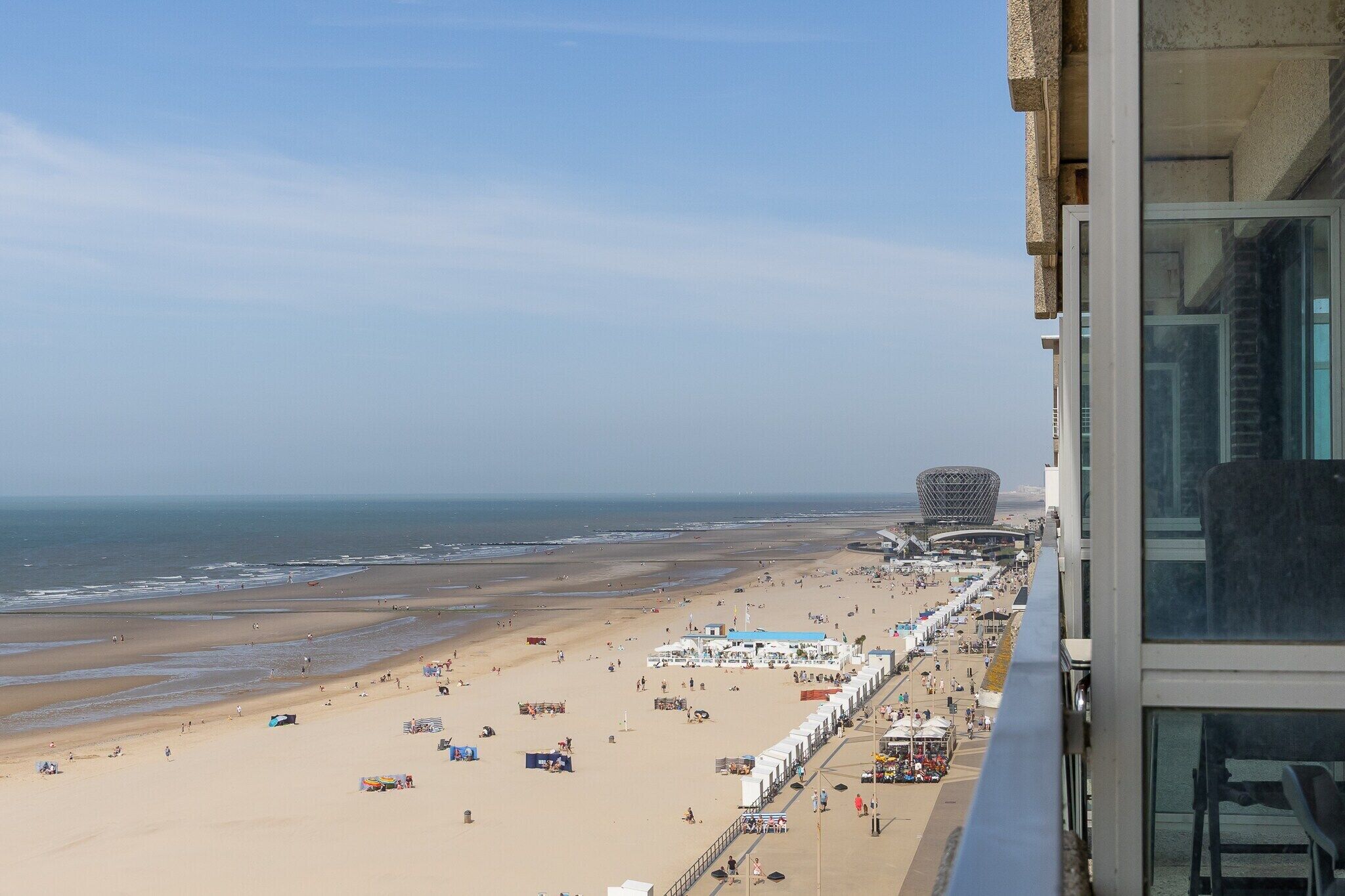 A beach with a view of the ocean and a distinctive building in the distance.