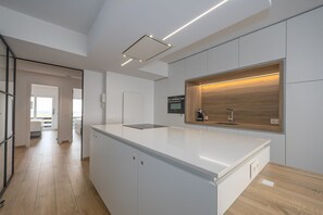 A modern kitchen with a central island, built-in appliances, and a view to the outside. - Luxurious apartment with stunning sea view (Middelkerke)