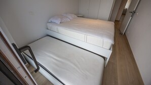 A small, compact room with a single bed, a bedside table, and a wardrobe. - Luxurious apartment with stunning sea view (Middelkerke)