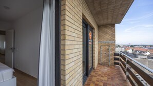 A balcony with a view of the city, a door with a sign, and a tiled floor. - Luxurious apartment with stunning sea view (Middelkerke)
