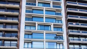 A modern multi-story building with a yellow sign indicating availability for short-term rentals. - Beautiful apartment with phenomenal sea view (Westende)
