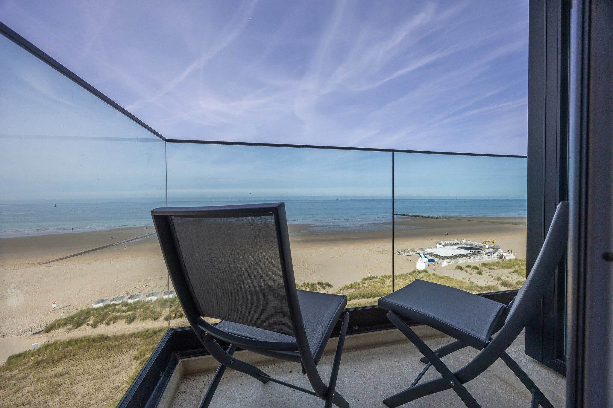 Un balcón con dos sillas que dan a vista de la playa.