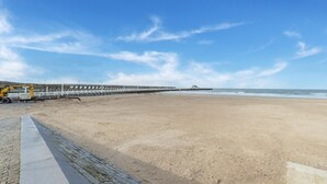 Ein Strand mit einem hölzernen Steg, der sich ins Meer erstreckt, einem klaren Himmel und einem Sandufer.