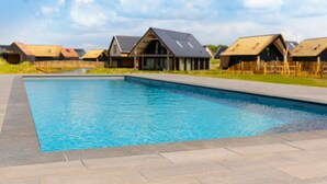 A swimming pool with a modern house in the background. - Holiday Home in Nieuwvliet-Bad near Beach (Nieuwvliet)