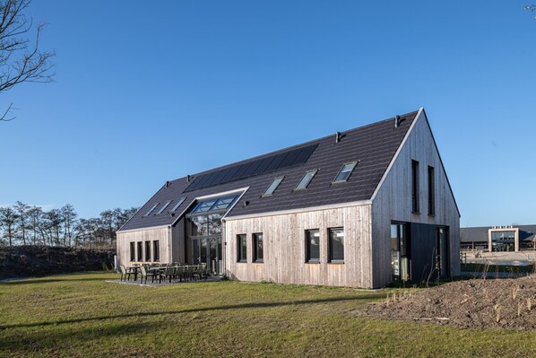 Een modern houten gebouw met een schuin dak en grote ramen.