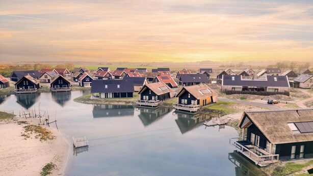 A row of traditional wooden houses with thatched roofs, connected by a waterway, and a dock extending into the water. - Holiday Home in Nieuwvliet-Bad near Beach (Nieuwvliet)