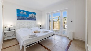 Une chambre à coucher comprenant un lit, des tables de chevet, un tableau et une porte-fenêtre coulissante donnant sur un espace extérieur.