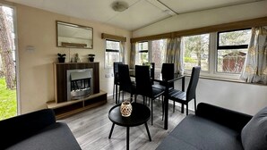 Un salón moderno con chimenea, muebles negros y ventanas amplias.
