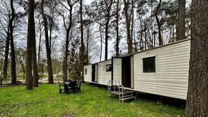 Una hilera de casas móviles en un área boscosa, con una mesa y sillas al frente.