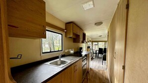 Una cocina compacta con armarios de madera, un lavamanos y una ventana que proporciona luz natural.