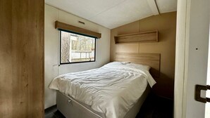 Un dormitorio con cama, ventana y cabecero de madera.