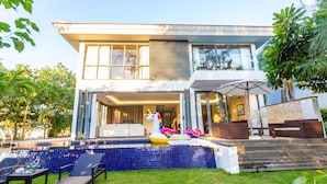 Ein modernes Haus mit Swimmingpool, einem Einhorn-Schwimmspielzeug und Sitzgelegenheiten im Freien.