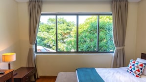 Ein Hotelzimmer mit einem Bett, einem Schreibtisch, einer Lampe und einem Vorhangfenster.