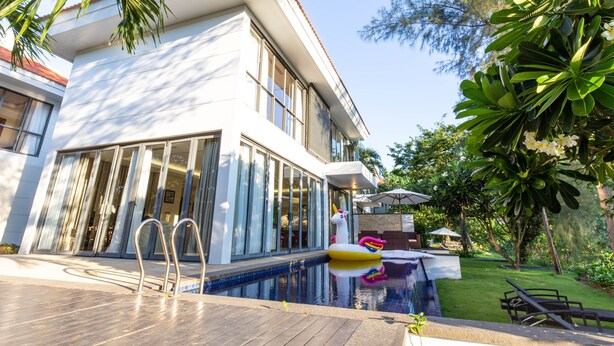 Ein modernes Haus mit Pool, einem Einhorn-Schwimmspielzeug und einem gepflegten Garten.