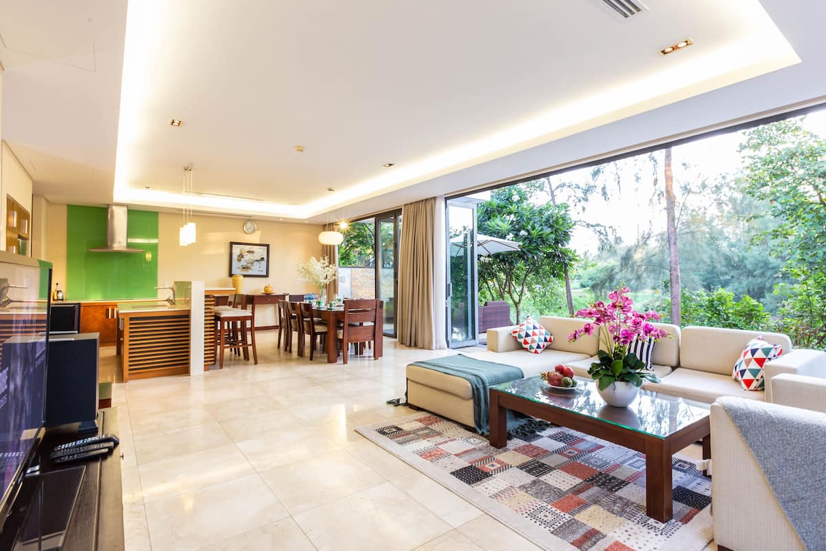 Uma sala de estar moderna com uma mesa de centro de vidro, um sofá e um espaço de refeições com mesa e cadeiras.