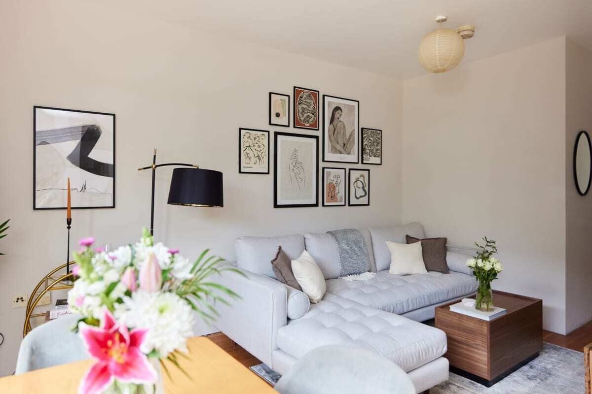 A modern living room with a light grey sofa, a wooden coffee table, and a wall adorned with framed artwork.