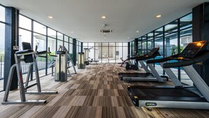 Une salle de sport équipée de tapis de course, de vélos d’appartement et d’appareils de musculation.