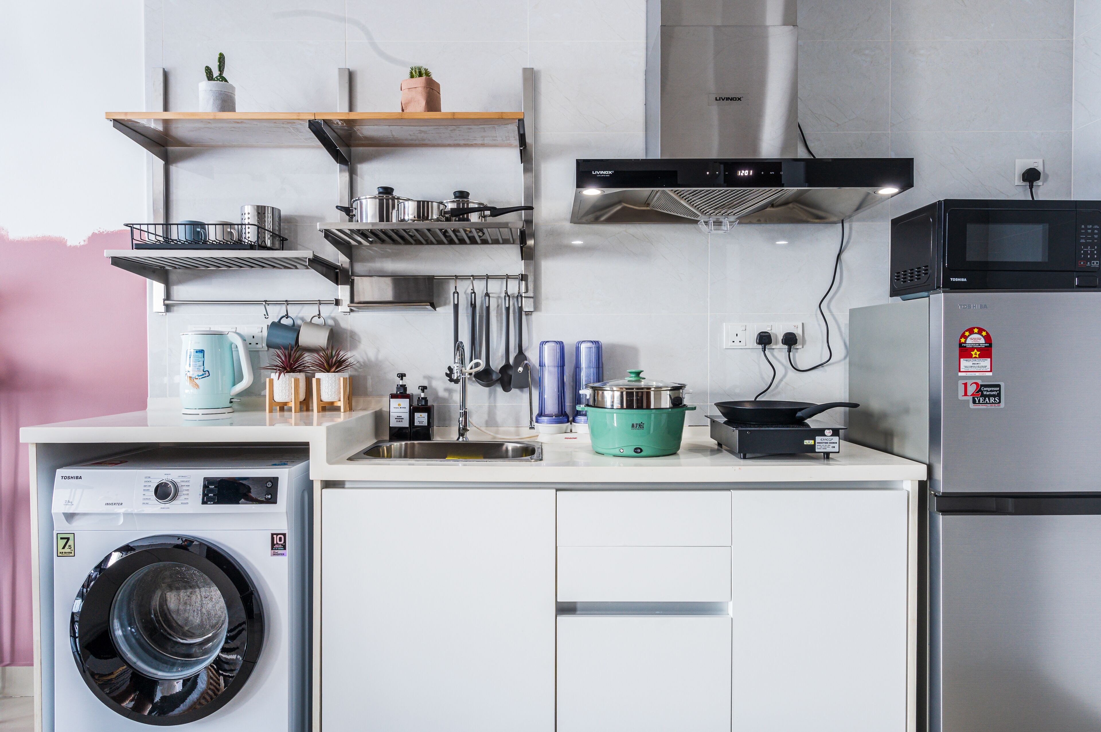 A compact kitchen with a washing machine, microwave, and various cooking utensils.