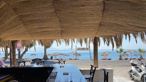 An outdoor seating area with a view of the beach and ocean. - MARMARAKI Village  (Kos)
