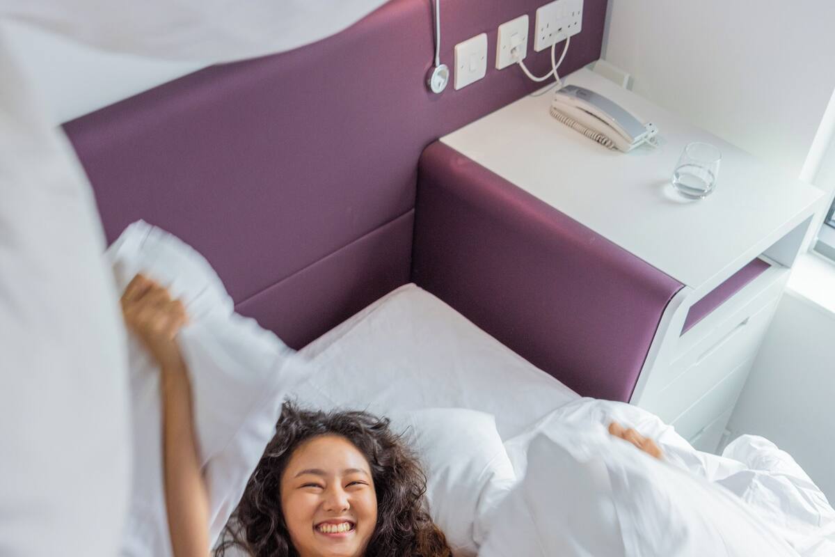 A bed with white bedding and a purple headboard.