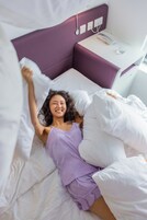 Una cama con ropa de cama blanca y un cabecero morado.